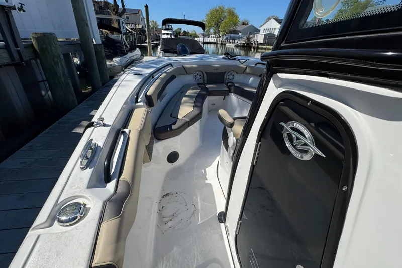 Slide: The Image of 2022 Tidewater 256 CC Adventure boat interior with seating and helm, docked at marina. - 16