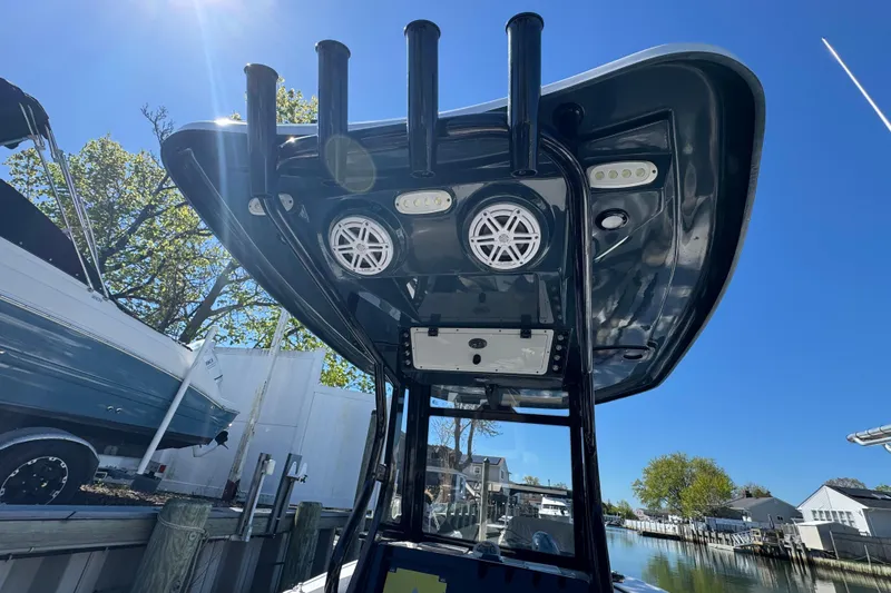Slide: The Image of 2022 Tidewater 256 CC Adventure boat with T-top speakers and rod holders, docked under clear blue sky. - 30