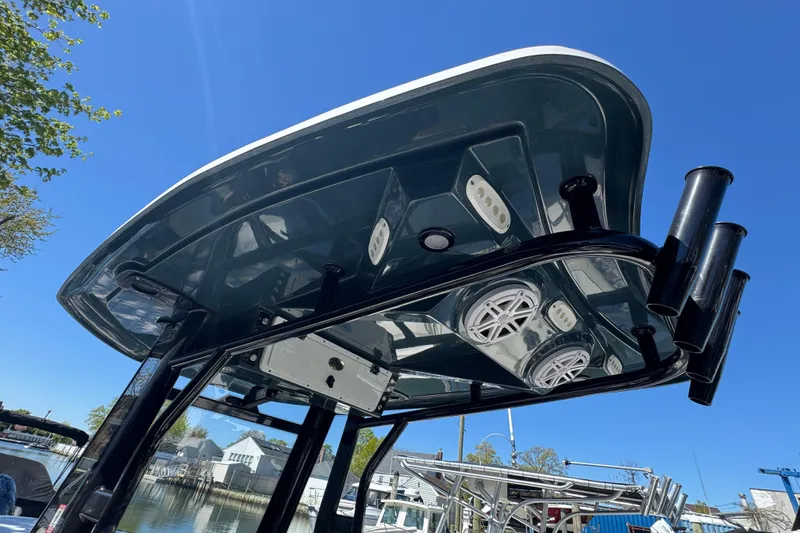 Slide: The Image of Tidewater 256 CC Adventure 2022 boat canopy with speakers and rod holders under clear blue sky. - 32