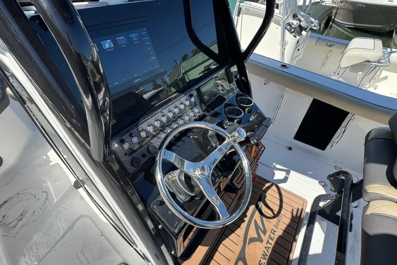 Slide: The Image of 2022 Tidewater 256 CC Adventure boat dashboard with steering wheel and control panel. - 7