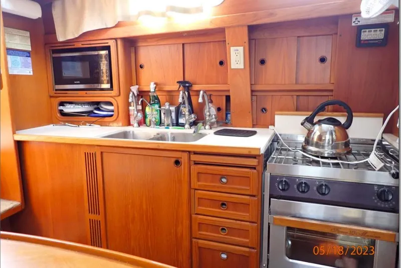 Slide: The Image of Wooden kitchen interior of 2001 Nauticat Staysail Ketch with stove, sink, and microwave. - 17