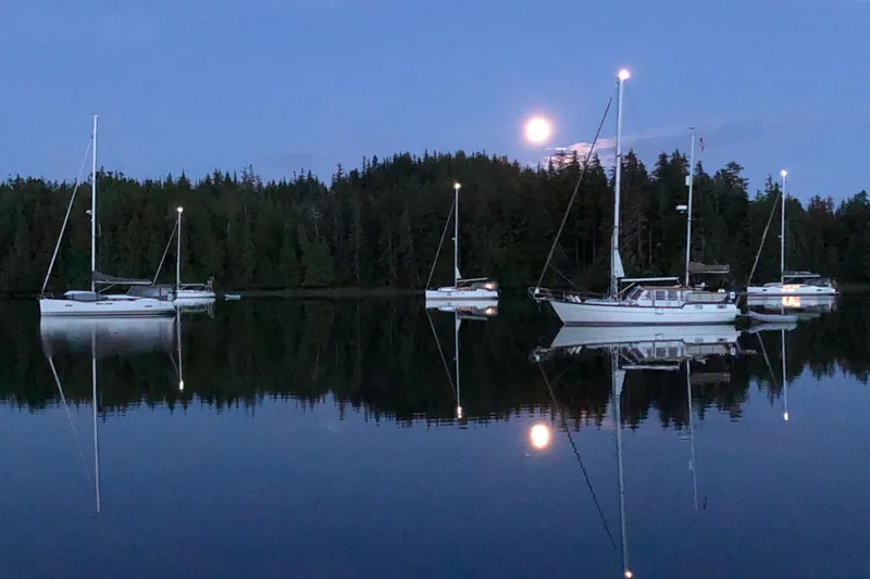 Slide: The Image of Sailboats, including a 2001 Nauticat Staysail Ketch, anchored on a serene lake under a full moon. - 2
