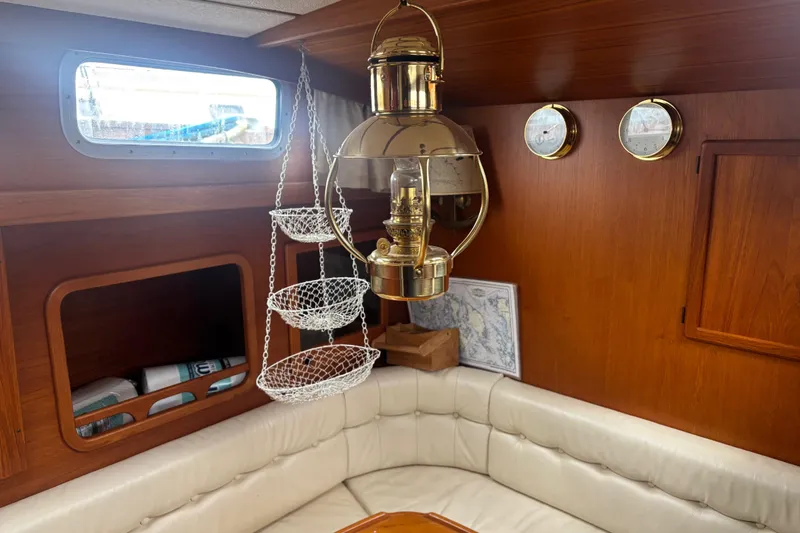 Slide: The Image of Interior of 2001 Nauticat Staysail Ketch with brass lamp and white seating. - 21