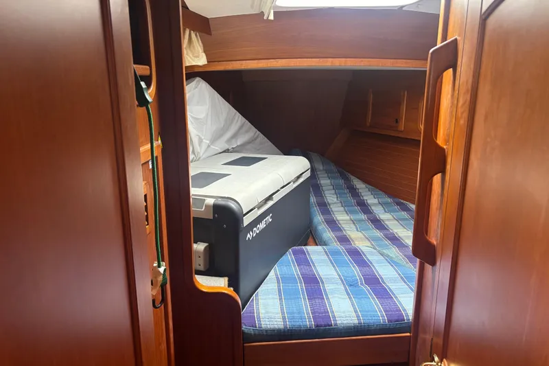 Slide: The Image of Cozy cabin interior of 2001 Nauticat Staysail Ketch with striped bedding and storage. - 25