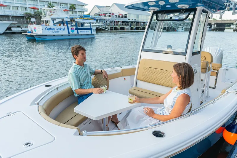 Slide: The Image of Manufacturer Provided Image: Couple relaxing on 2025 Sportsman Open 212 Center Console boat, enjoying drinks by the water. - 23