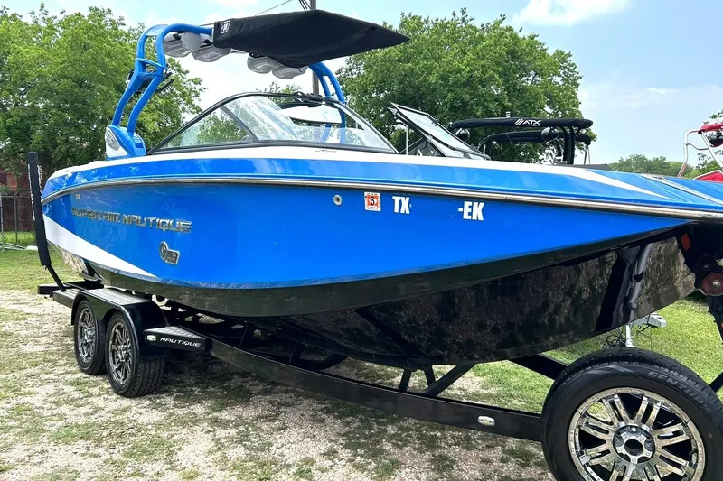 Slide: The Image of 2013 Nautique Super Air Nautique G23 boat in vibrant blue on a trailer. - 11