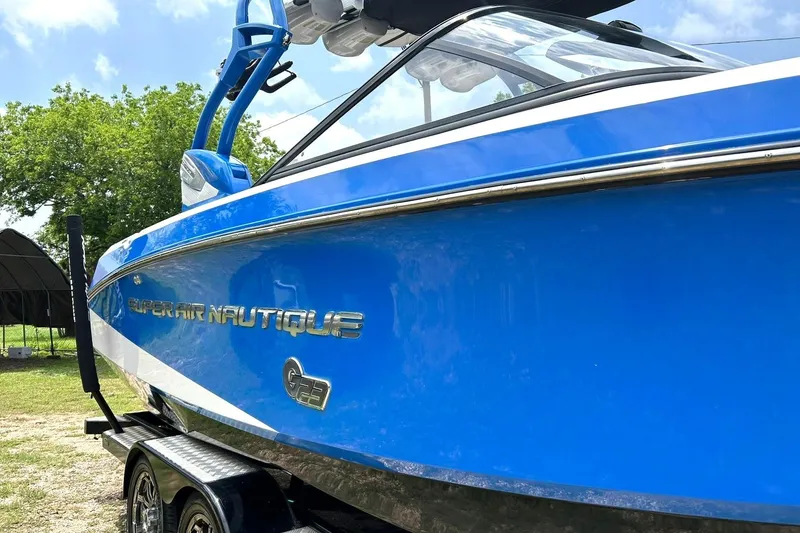 Slide: The Image of 2013 Nautique Super Air Nautique G23 boat in vibrant blue, parked outdoors. - 12