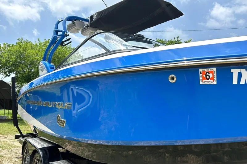 Slide: The Image of 2013 Nautique Super Air Nautique G23 boat in vibrant blue, parked outdoors. - 13