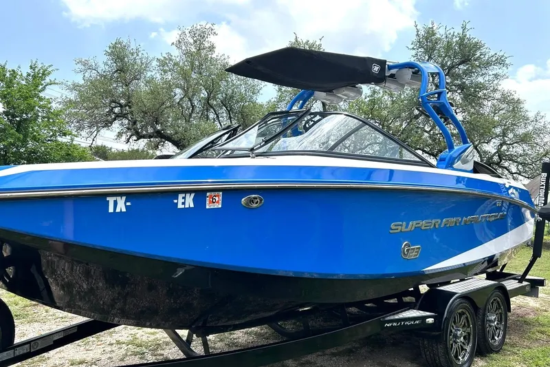 Slide: The Image of 2013 Nautique Super Air Nautique G23 boat in vibrant blue on a trailer. - 2