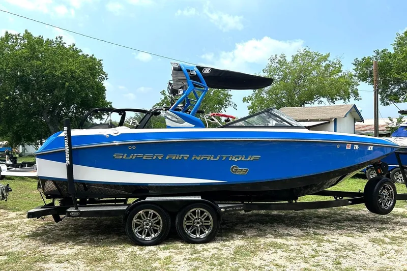 Slide: The Image of 2013 Nautique Super Air Nautique G23 boat in blue on trailer, outdoors. - 6