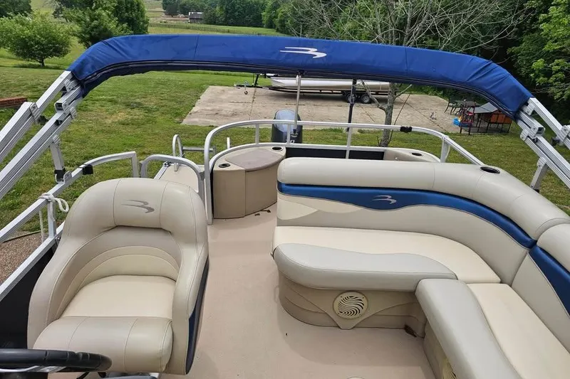 Slide: The Image of 2012 Sweetwater 20sf pontoon boat with beige and blue seating, set in a grassy area. - 6