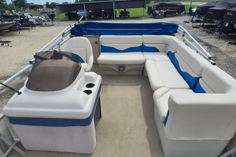 Slide: The Image of 2003 Sun Tracker Party Barge 24 with spacious seating and helm, parked outdoors. - 5