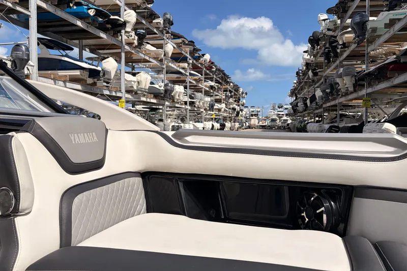 Slide: The Image of 2021 Yamaha Boats 275SD interior with marina backdrop, showcasing luxury seating and storage. - 35