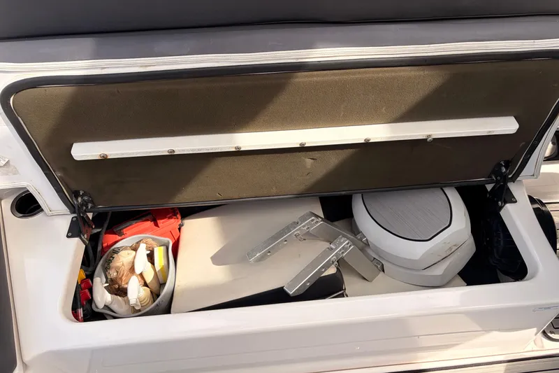Slide: The Image of Open storage compartment in 2021 Yamaha Boats 275SD, showing various items and equipment. - 44