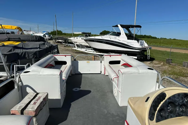 Slide: The Image of 1999 PlayCraft Sport 2400 pontoon boat with white seating, docked near other boats. - 14