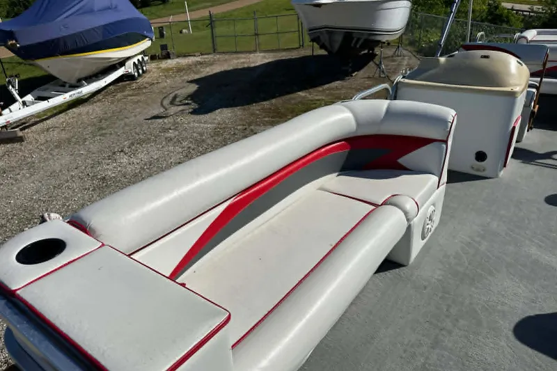 Slide: The Image of 1999 PlayCraft Sport 2400 boat interior with red and white seating, parked outdoors. - 15