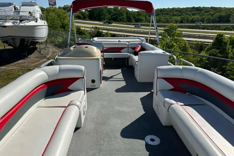 Slide: The Image of 1999 PlayCraft Sport 2400 pontoon boat with red and white seating, docked outdoors. - 16
