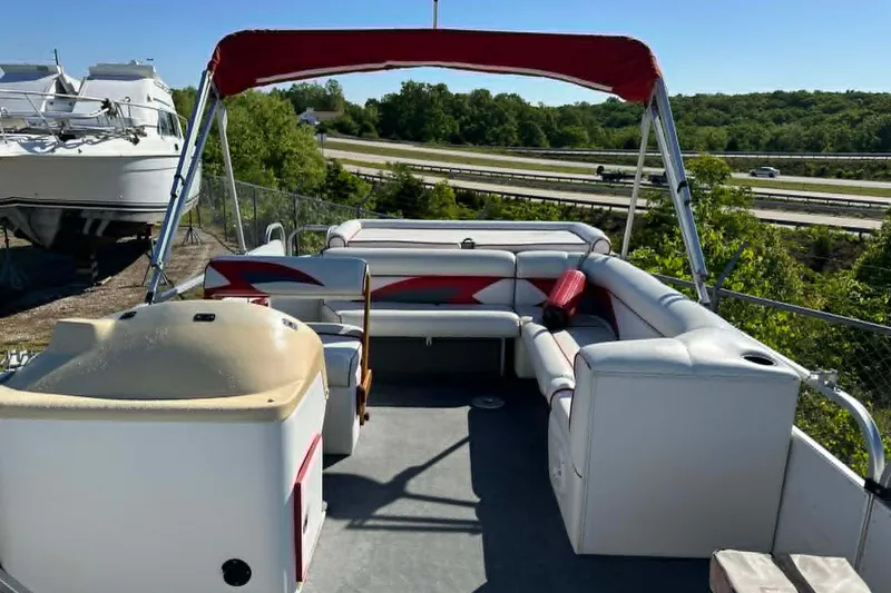 Slide: The Image of 1999 PlayCraft Sport 2400 pontoon boat with red canopy, parked near highway. - 9