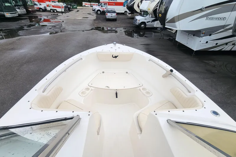 Slide: The Image of 2006 Mako 216 Dual Console boat interior with seating and storage, parked near RVs. - 11