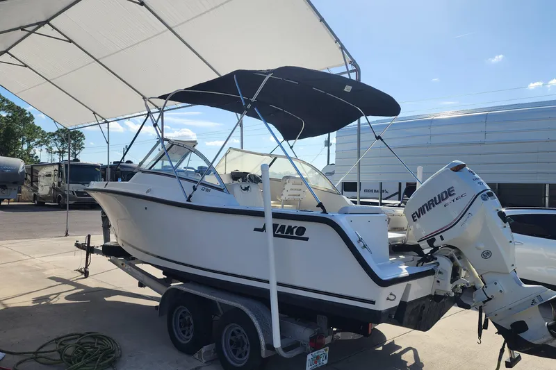 Slide: The Image of 2006 Mako 216 Dual Console boat on trailer under canopy, featuring Evinrude outboard motor. - 17