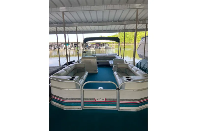 Slide: The Image of 1995 PlayCraft Powertoon 26 pontoon boat docked under a covered marina. - 10