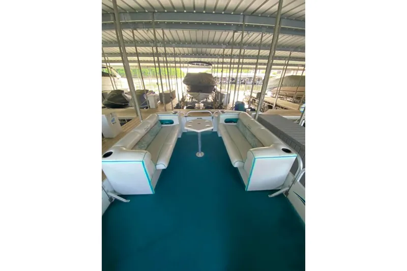 Slide: The Image of 1995 PlayCraft Powertoon 26 interior with teal carpet and white seating in a covered dock. - 14