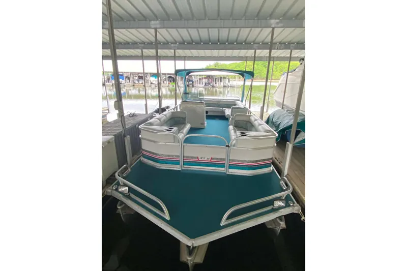 Slide: The Image of 1995 PlayCraft Powertoon 26 pontoon boat docked under a covered marina. - 15