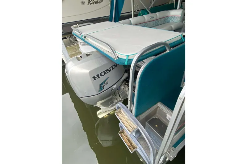 Slide: The Image of 1995 PlayCraft Powertoon 26 with Honda outboard motor, docked on calm water. - 2
