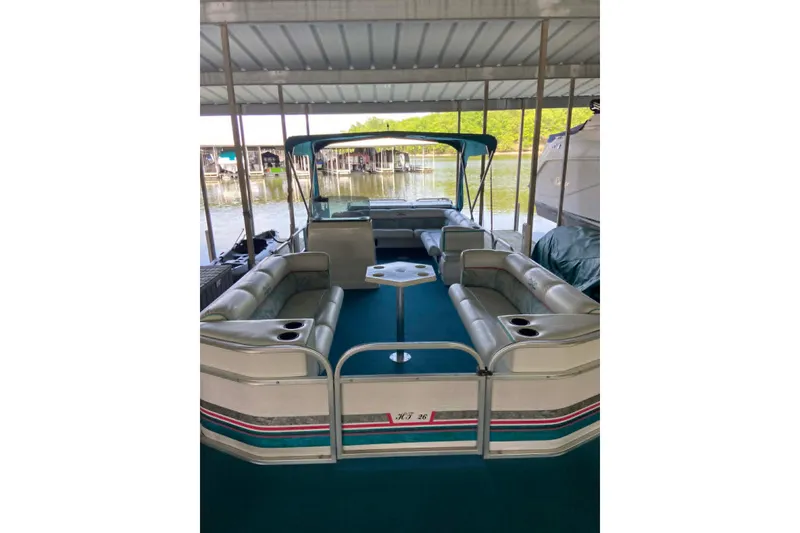 Slide: The Image of 1995 PlayCraft Powertoon 26 pontoon boat with spacious seating under a covered dock. - 5