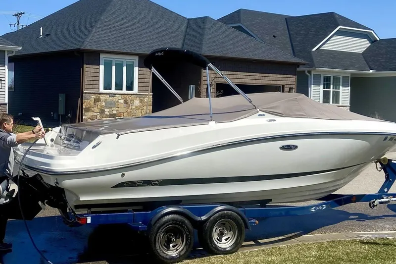The Image of 2012 Sea Ray SLX 230 boat on trailer, parked in residential driveway. - 0