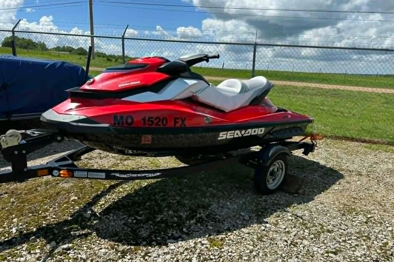 The Image of Red 2012 Sea-Doo GTI SE 130 jet ski on trailer, parked outdoors under a cloudy sky. - 1