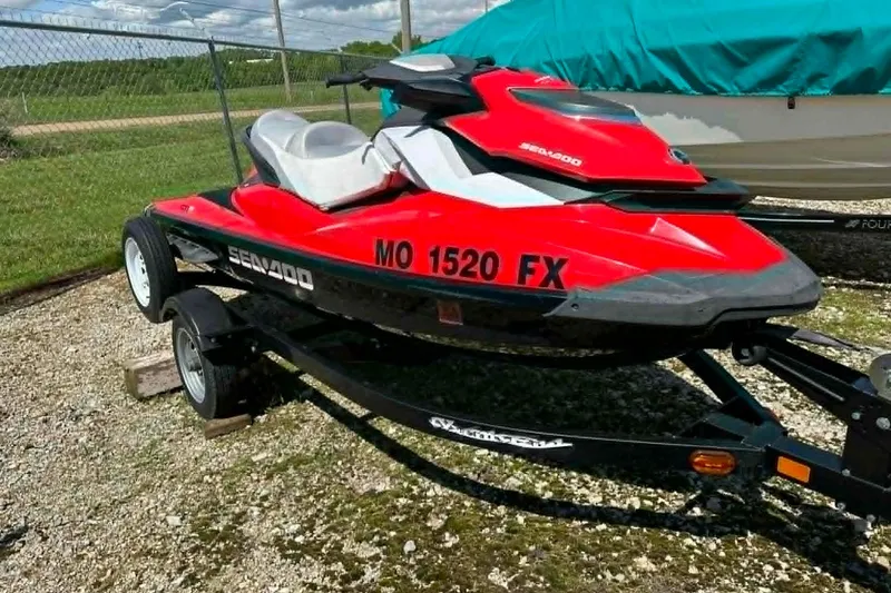 Slide: The Image of 2012 Sea-Doo GTI SE 130 jet ski on trailer, vibrant red color, parked outdoors. - 2