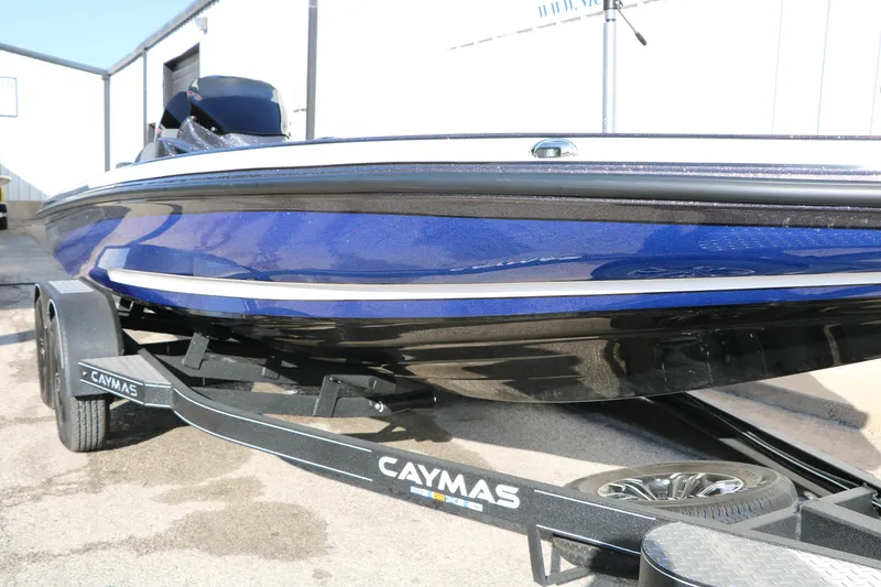 Slide: The Image of 2027 Caymas 201 Pro boat on trailer, blue and black design, parked outdoors. - 14