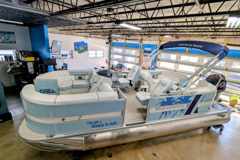 Slide: The Image of 2026 Trifecta CS 22RF pontoon boat in a garage, featuring "License to Chill" design. - 2