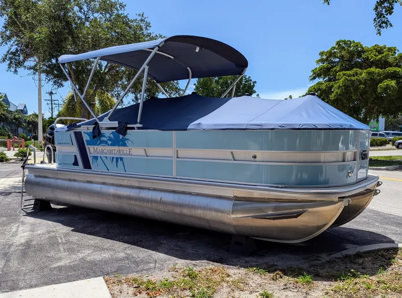 Slide: The Image of 2026 Trifecta CS 22RF pontoon boat with blue cover, parked outdoors. - 23
