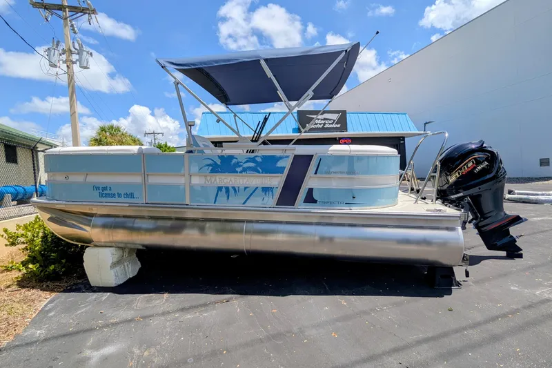 Slide: The Image of 2026 Trifecta CS 22RF pontoon boat with canopy and outboard motor, parked outdoors. - 9