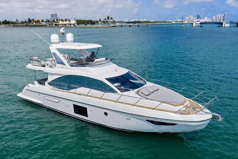 The Image of Luxurious 2019 Azimut yacht cruising in clear blue waters near a city skyline. - 0