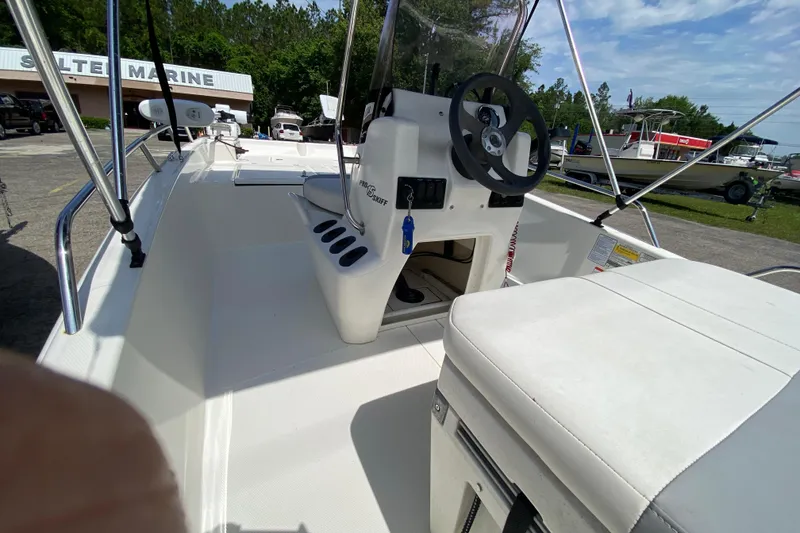 Slide: The Image of 2021 Mako Pro Skiff 15 CC boat interior with steering wheel and seating, at a marine dealership. - 6