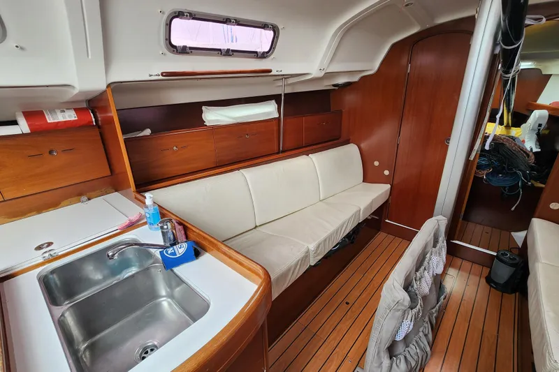 Slide: The Image of Interior of 2004 Beneteau First 36.7 sailboat with wooden cabinetry and white seating. - 12