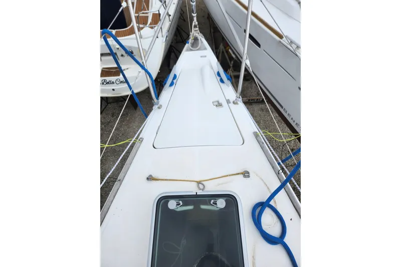 Slide: The Image of 2004 Beneteau First 36.7 sailboat deck with ropes and hatch, docked alongside other boats. - 7