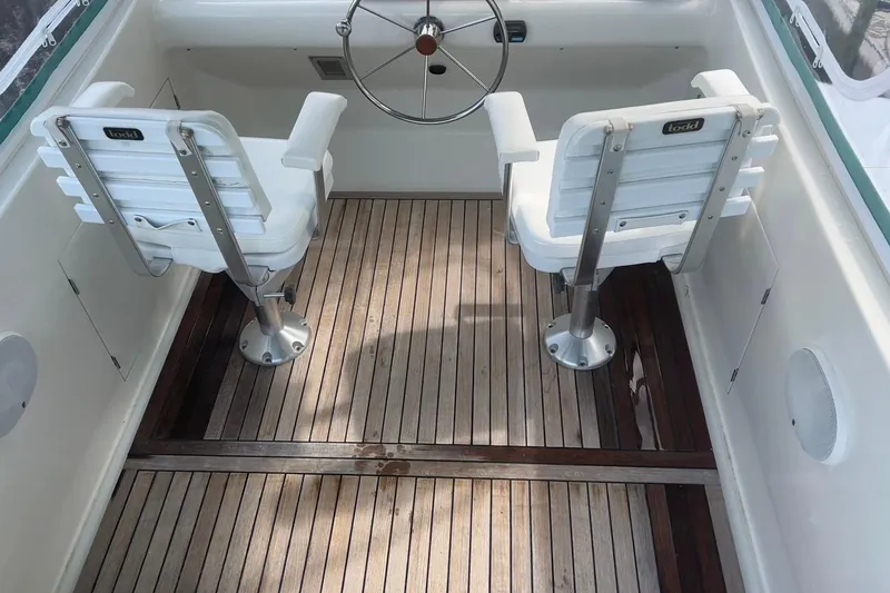 Slide: The Image of Cockpit of 2002 Custom 64 Stuart Catamarans with wooden flooring and two white seats. - 11