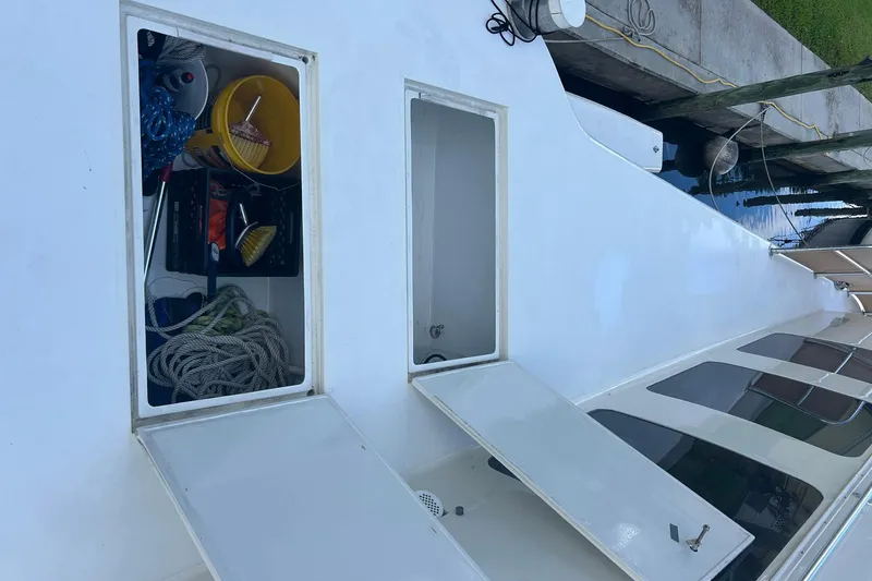 Slide: The Image of Open storage compartments on 2002 Custom 64 Stuart Catamarans deck, showing ropes and cleaning supplies. - 19