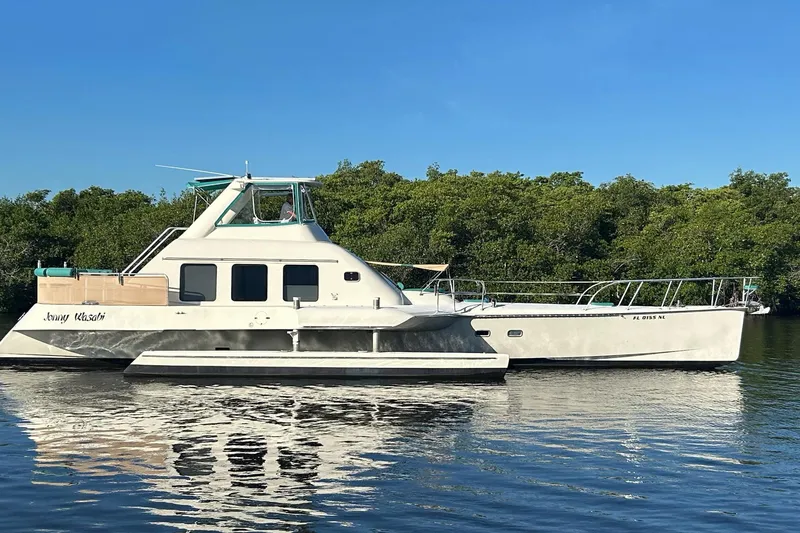 The Image of Custom 64 Stuart Catamarans 2002 on calm water, surrounded by lush greenery. - 2