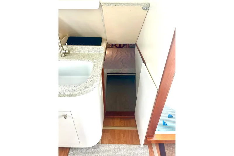 Slide: The Image of Interior of 2002 Custom 64 Stuart Catamarans, featuring a compact kitchen area. - 32