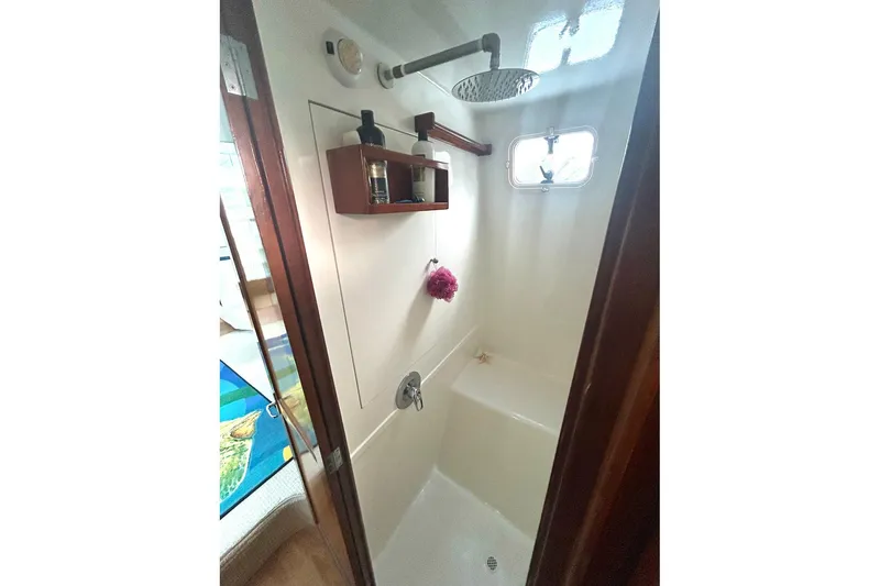 Slide: The Image of Shower area in 2002 Custom 64 Stuart Catamarans, featuring a rain showerhead and small window. - 39