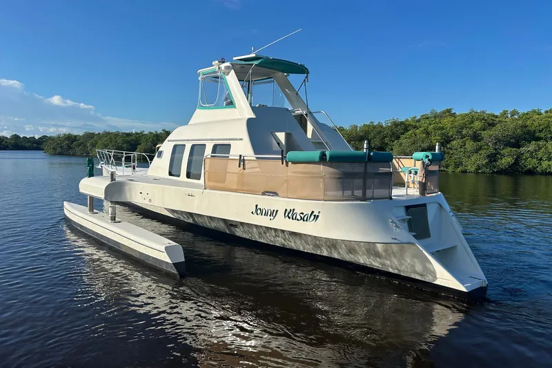 Slide: The Image of Custom 64 Stuart Catamarans 2002 on calm water, surrounded by lush greenery. - 4