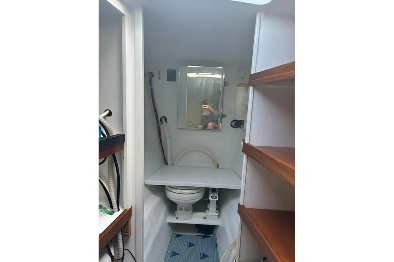 Slide: The Image of Compact bathroom on 2002 Custom 64 Stuart Catamarans, featuring toilet, mirror, and shelving. - 42