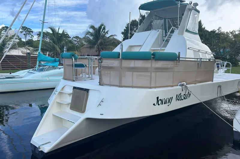 Slide: The Image of Custom 64 Stuart Catamarans 2002 docked, featuring teal accents and tropical surroundings. - 7