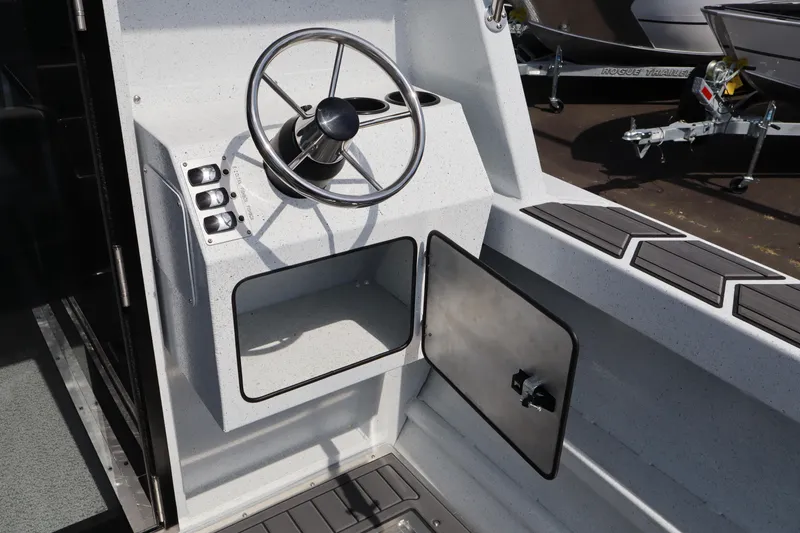 Slide: The Image of Steering console of 2026 KingFisher 25 XAC boat with modern controls and storage compartment. - 10