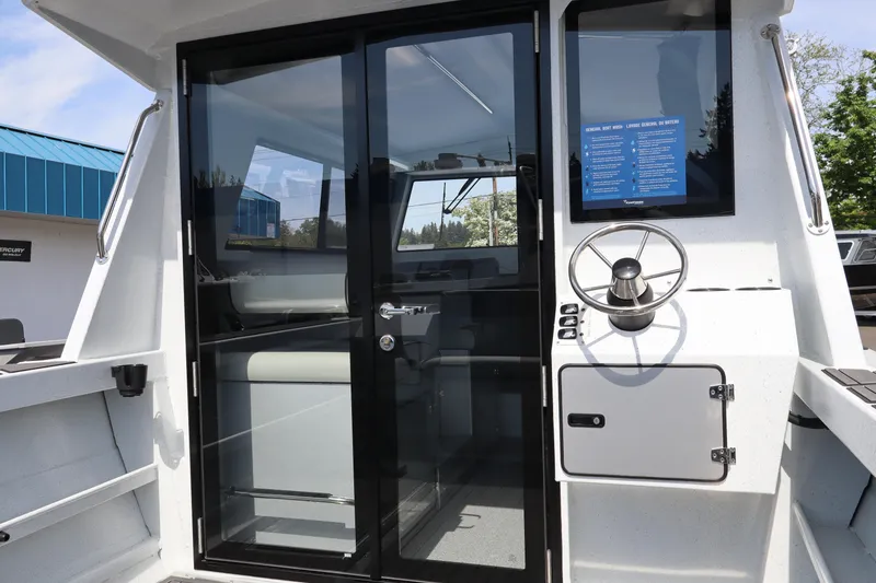 Slide: The Image of 2026 KingFisher 25 XAC boat interior with steering wheel and glass door. - 11